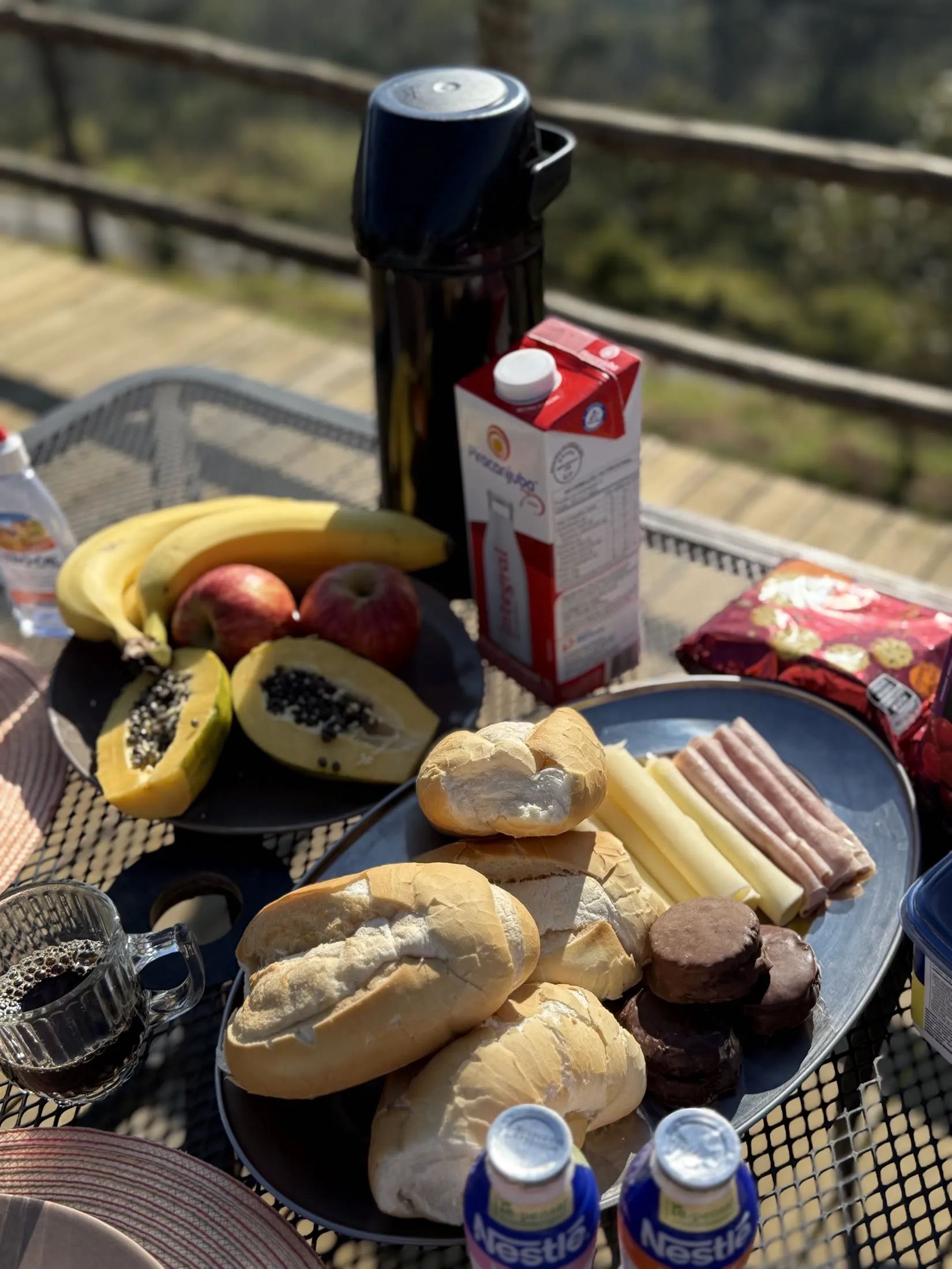 Mesa de café da manhã com pães, frutas e frios