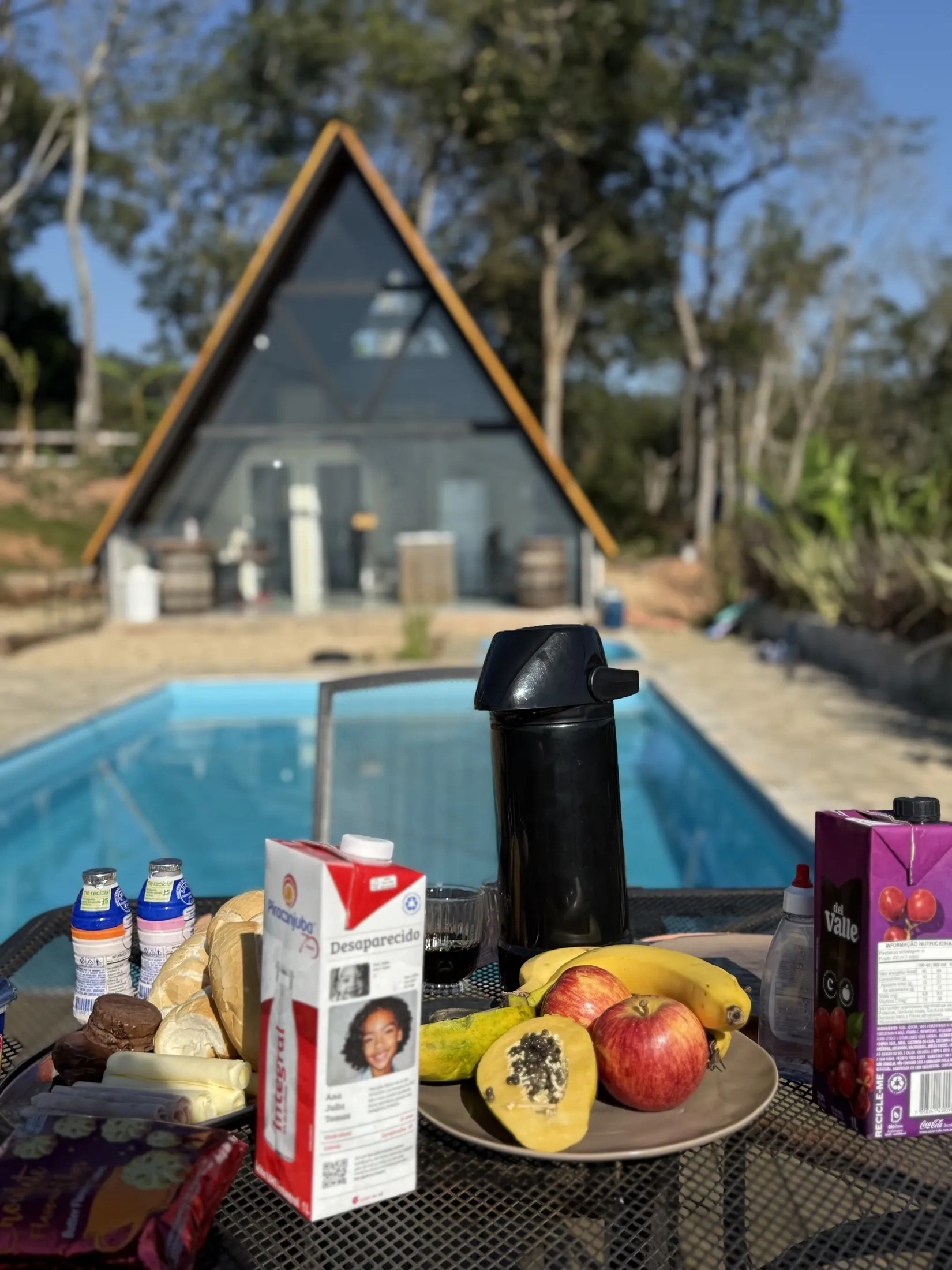 Café da manhã servido à beira da piscina, com o chalé ao fundo